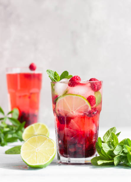 Pink cocktail or lemonade with raspberries, mint, lime and ice on a grey concrete table. Summer refreshment drink. Pink cocktail or lemonade with raspberries, mint, lime and ice on a grey table. Summer refreshment drink. pink tea stock pictures, royalty-free photos & images