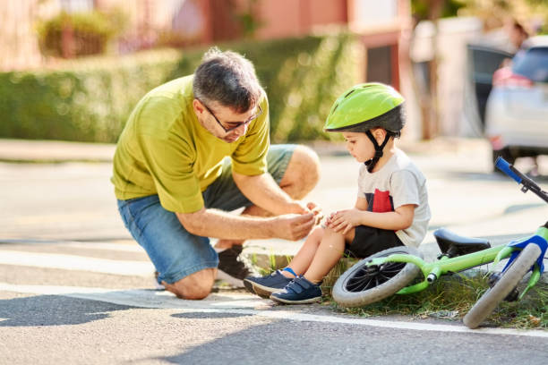 Father helping son with bandage Shot of a father applying antibacterial medical bandage on child's knee after falling down from a cycle human knee stock pictures, royalty-free photos & images