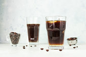 Espresso tonic, refreshment summer drink with tonic water, coffee and ice cubes, light grey concrete background. Trendy coffee drink.