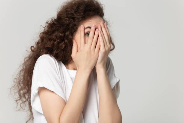 istock Afraid millennial girl hiding peeping through fingers 1251191193