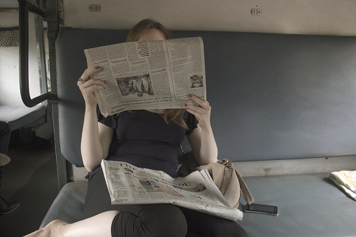 Newspaper reading girl in an Indian passenger train