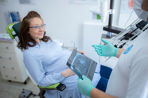 Dentist discussing with his female patient and showing her x-ray scans