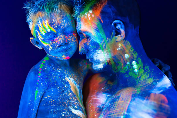 istock Young father and son. Painted with fluorescent paint using UV light 1251194064