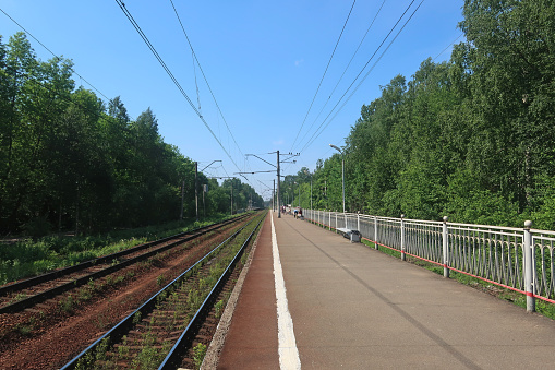 railway tracks and an asphalt-paved railway platform with a white boundary line at the edge of the platform