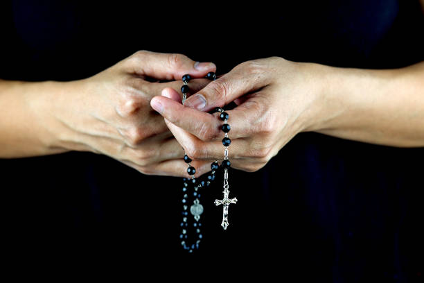 istock Womans Hands with Rosary Against a Dark Shirt 1251198887