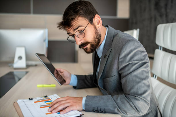 istock a young business man sits in an office and compares data from a paper and a note pad 1251200173