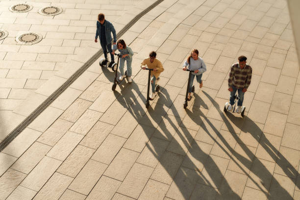 Full-length portrait of a group of millennials having fun while riding electric scooters and segways along the city. Ecological transportation, urban lifestyle concept. Horizontal shot. Top view