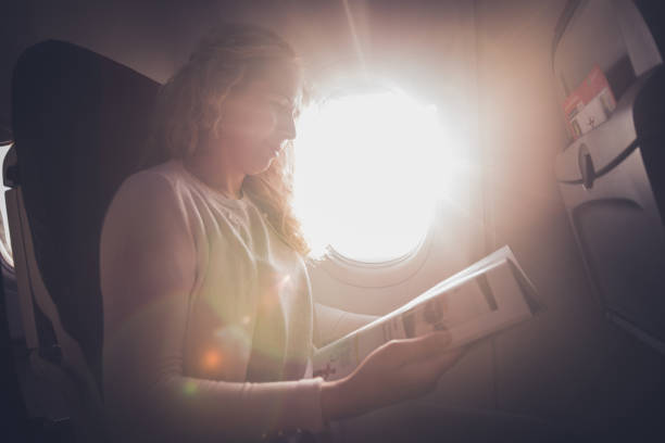 istock Curly woman reading newspaper in airplane. 1251200282