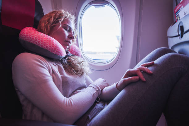 una pasajera que duerme con el cojín del cuello en el avión. - silla al lado de la ventana fotografías e imágenes de stock