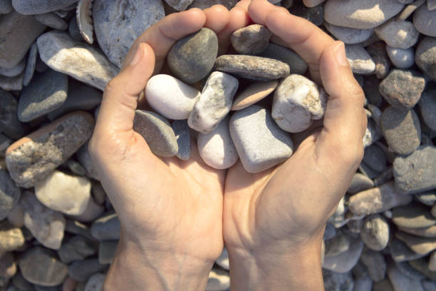 istock Woman hands touching stones on the beach. Grey stones 1251203104