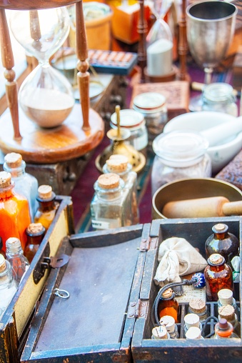 Lot of ancient alchemist instruments, medicine, boxes and bottles over a table