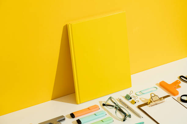 Yellow blank hardcover book mockup, template on yellow and white background. Stationary flat lay, knolling