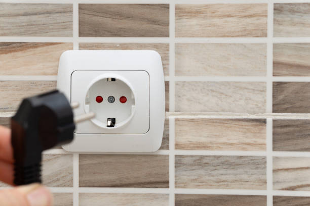 istock Installing plug into the electrical outlet on the wall 1251212810