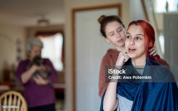 Older Sister Cutting Her Younger Sisters Hair At Home And Their Grandmother Is Wathcing With A Puppy Dog In Her Hands Stock Photo - Download Image Now