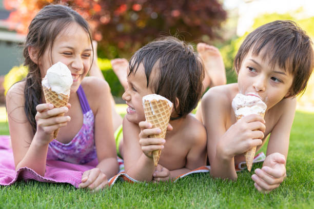istock Three Young Siblings Sitting Together Eating Ice Cream Cones On A Warm Summer Day 1251219164