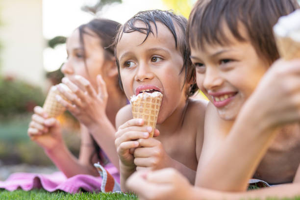 istock Three Young Siblings Sitting Together Eating Ice Cream Cones On A Warm Summer Day 1251219169