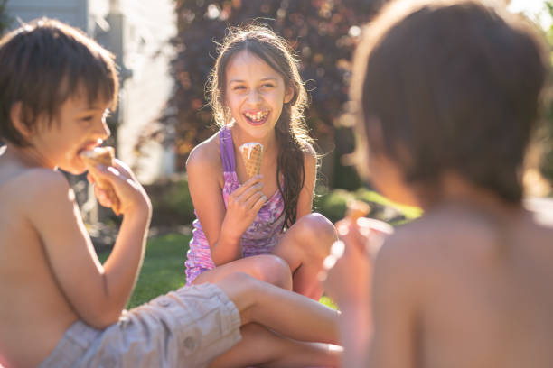 istock Three Young Siblings Sitting Together Eating Ice Cream Cones On A Warm Summer Day 1251219176