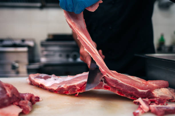 istock Male chef cutting raw pork ribs in restaurant kitchen 1251219200