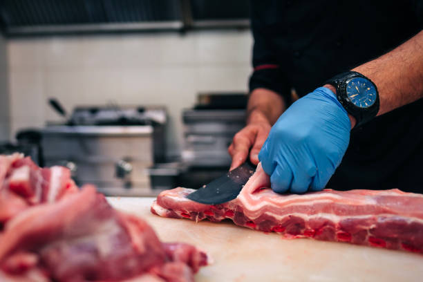 istock Male chef cutting raw pork ribs in restaurant kitchen 1251219201