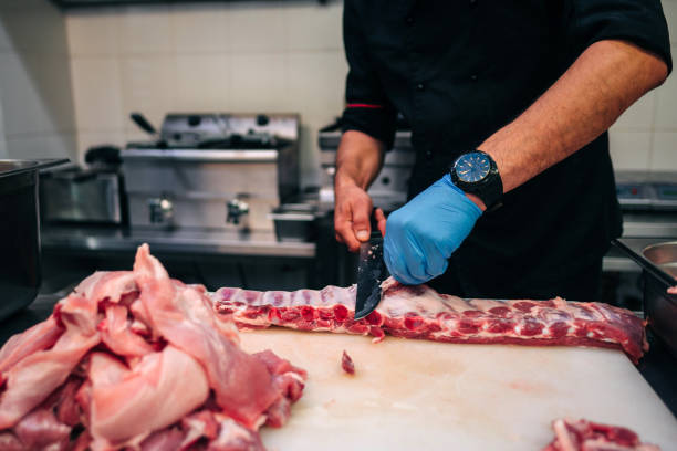 istock Male chef cutting raw pork ribs in restaurant kitchen 1251219202