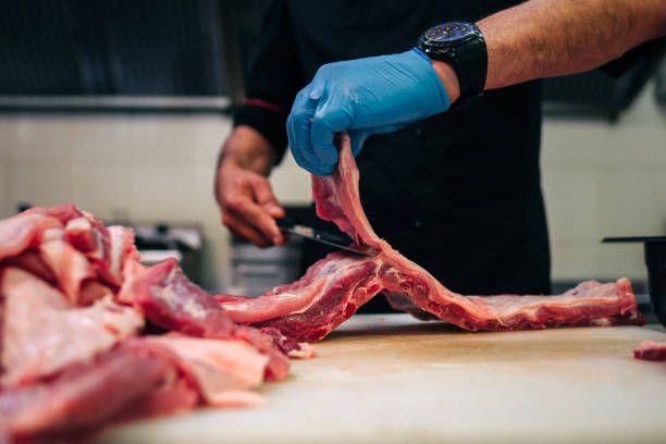 istock Male chef cutting raw pork ribs in restaurant kitchen 1251219204