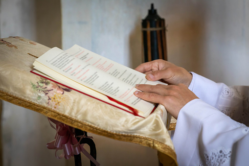 The hands of the priest holding the bible during the mass.
