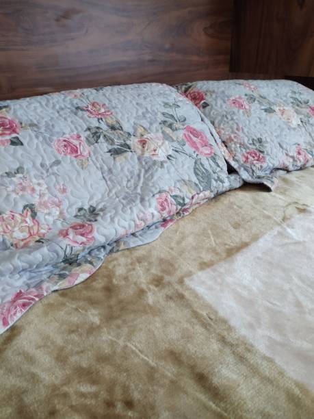 istock Flower-patterned pillows on a bed shot against a wooden background. 1251221441