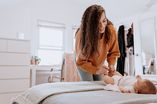 Mixed race latin mother changing her baby diaper