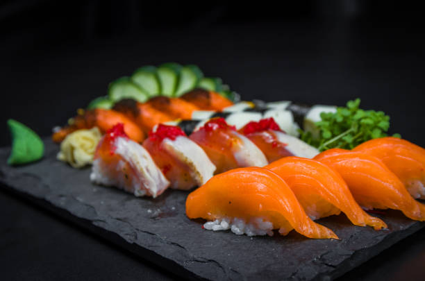 sushi, cocina tradicional japonesa. varios deliciosos sushi en el plato decorado, fondo negro. grupo de sushi, urakami, nigori, sushi jow, sashimi, tekamaki, etc... - niguiri sushi fotografías e imágenes de stock