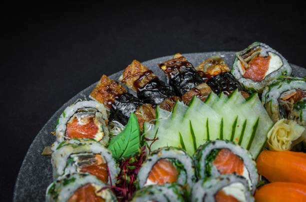 sushi, cocina tradicional japonesa. varios deliciosos sushi en el plato decorado, fondo negro. grupo de sushi, urakami, nigori, sushi jow, sashimi, tekamaki, etc... - niguiri sushi fotografías e imágenes de stock