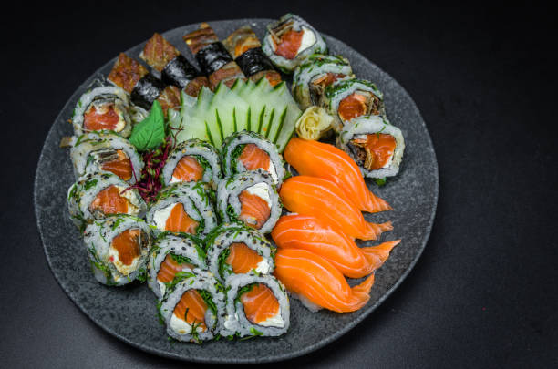 sushi, cocina tradicional japonesa. varios deliciosos sushi en el plato decorado, fondo negro. grupo de sushi, urakami, nigori, sushi jow, sashimi, tekamaki, etc... - niguiri sushi fotografías e imágenes de stock