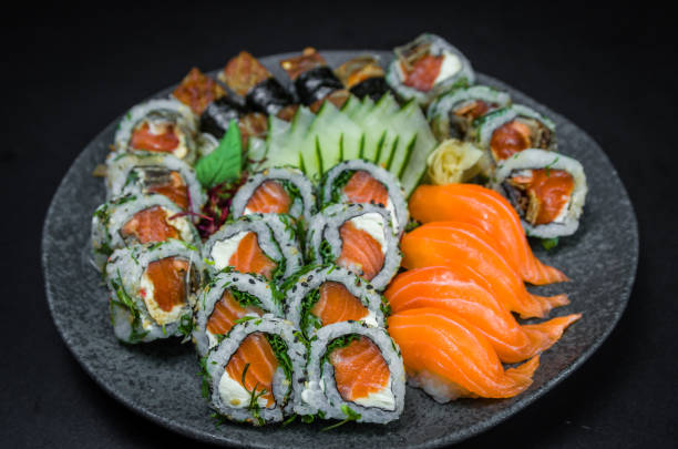 sushi, cocina tradicional japonesa. varios deliciosos sushi en el plato decorado, fondo negro. grupo de sushi, urakami, nigori, sushi jow, sashimi, tekamaki, etc... - niguiri sushi fotografías e imágenes de stock
