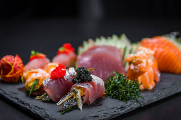 sushi, tradycyjne dania kuchni japońskiej. kilka pysznych sushi na zdobionym talerzu, czarne tło. grupa sushi, urakami, nigori, sushi jow, sashimi, tekamaki itp ... - niguiri sushi zdjęcia i obrazy z banku zdjęć