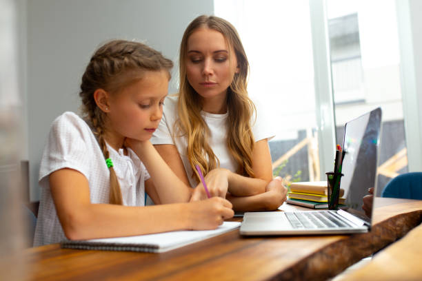 istock Loving mother helping daughter to study at home 1251228646