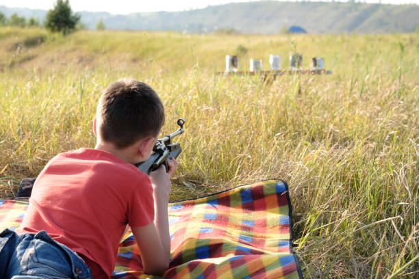 młody chłopak strzelanie z karabinu pneumatycznego (krajobraz) - air rifle zdjęcia i obrazy z banku zdjęć