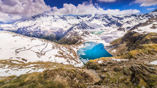 estrada montanhosa e lago agnel e serru à distância, paisagem coberta de neve – gran paradiso, itália - parque nacional de gran paradiso - fotografias e filmes do acervo