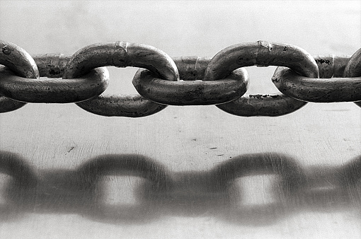 A close up of a chain and it reflection on a metal door.