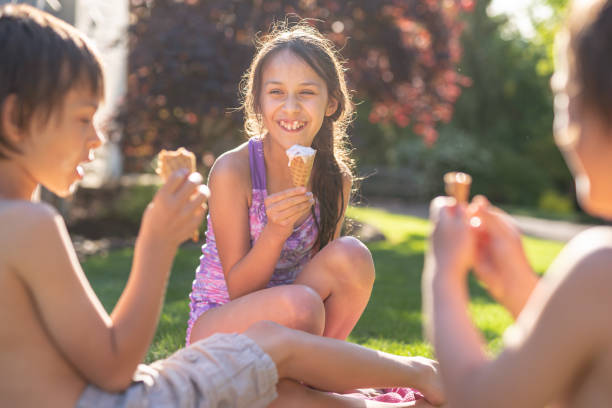 istock Three Young Siblings Sitting Together Eating Ice Cream Cones On A Warm Summer Day 1251251214