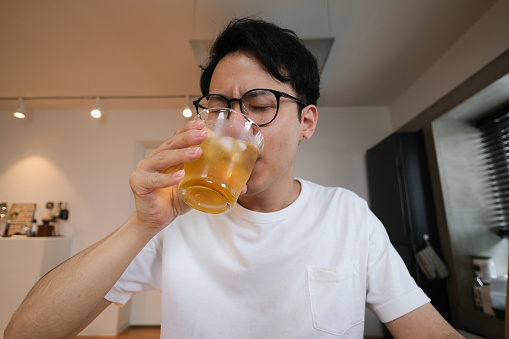 Asian mid adult man joining to online happy hour from home