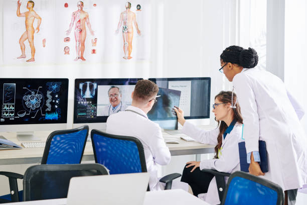 Researchers talking to pulmonologist Group of medical researchers discussing lungs x-ray of patient with experienced pulmonologist health technology photos stock pictures, royalty-free photos & images