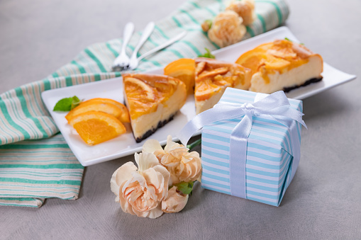 Composition with gift box and orange cheese cakes on table. Father's day celebration