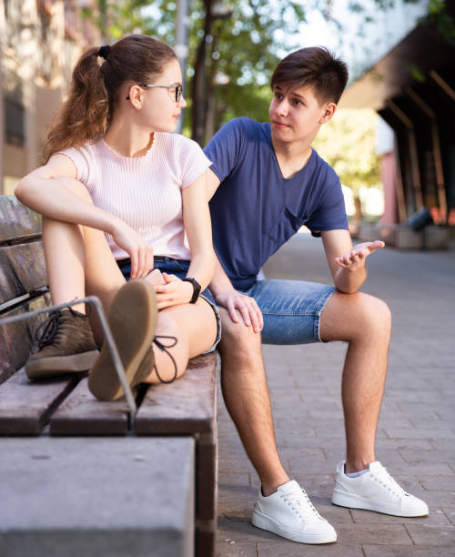 istock Two teenagers using smartphones sitting on bench 1251267071