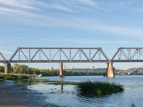 Left-bank part of the railroad bridge made of steel trusses and stone supports across river. Podilskyi Railroad Bridge across Dnieper River​, Kyiv, Ukraine