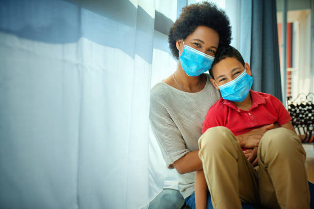 istock Mother and son in pandemic quarantine looking though window. 1251268324