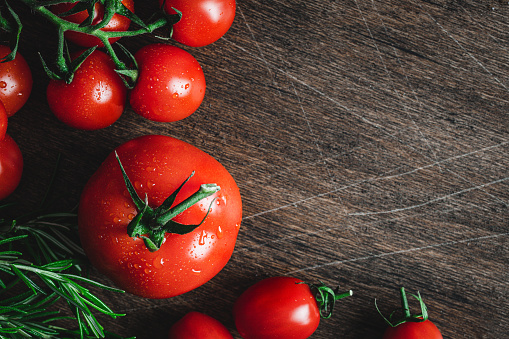 Top view of fresh organic tomatoes on rustic wood background with copy space. Fresh ripe tomatoes on a wooden dark background.