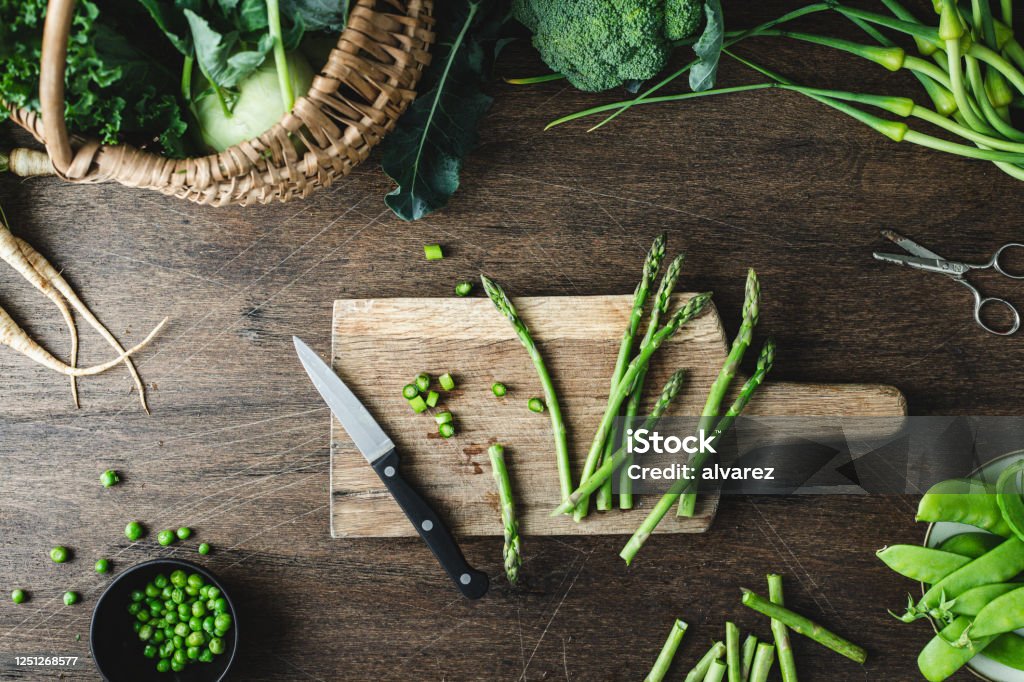 Asparagus on a wooden chopping board Top view of asparagus on a wooden chopping board with kitchen knife on wooden table. Cutting asparagus on a chopping board in kitchen. Asparagus Stock Photo