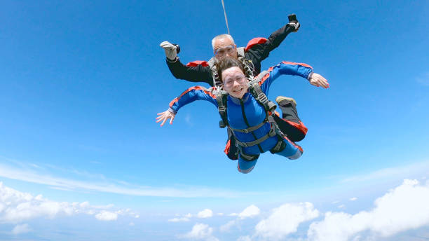 istock Happy woman enjoy free fall with experienced parachuting instructor. 1251268710