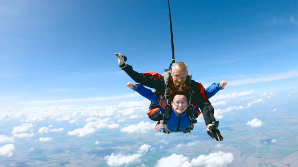 istock Happy woman enjoy free fall with experienced parachuting instructor. 1251268711