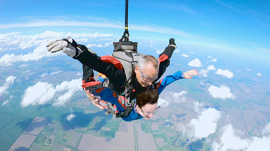 A woman is enjoying her first parachute jump. She jumped with an experienced skydiving instructor.