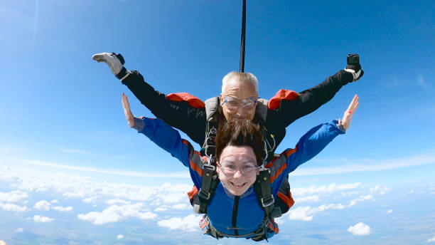 A woman is enjoying her first parachute jump. She jumped with an experienced skydiving instructor.